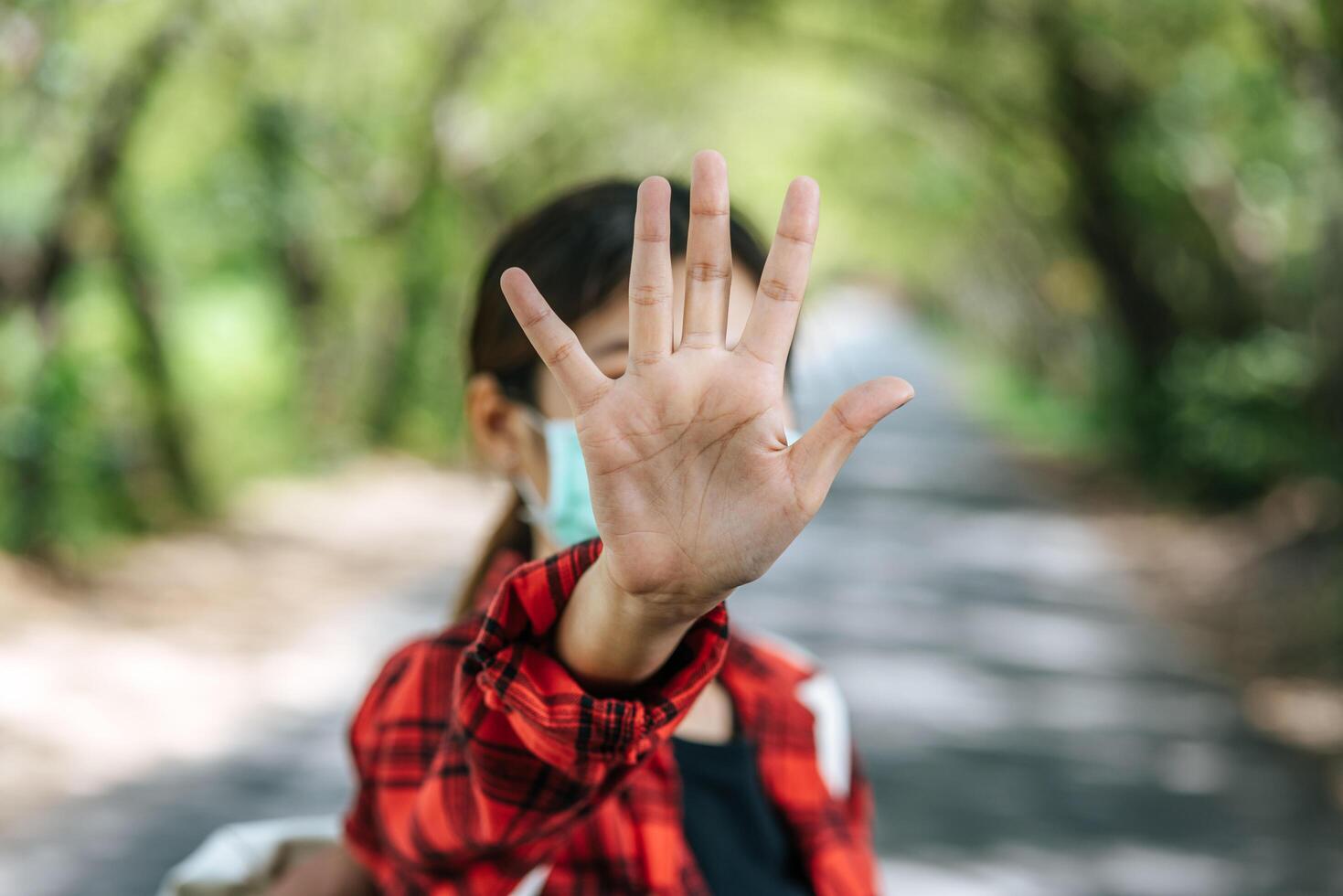 A female tourist carrying a backpack and raising her five fingers to ban on the road. photo