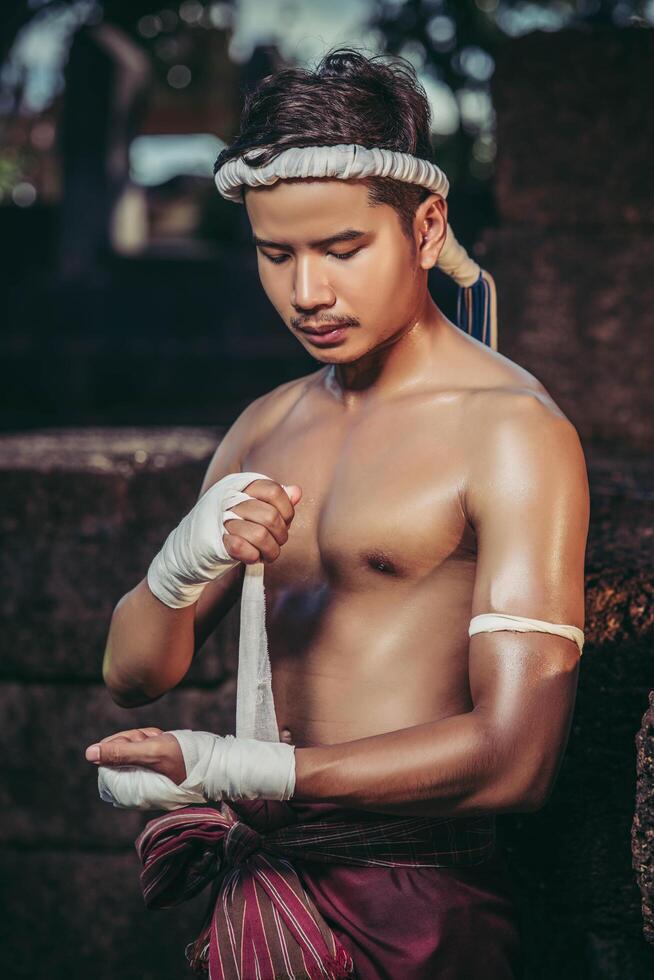 The boxer sat on the stone, tied the tape around his hand, preparing to fight. photo