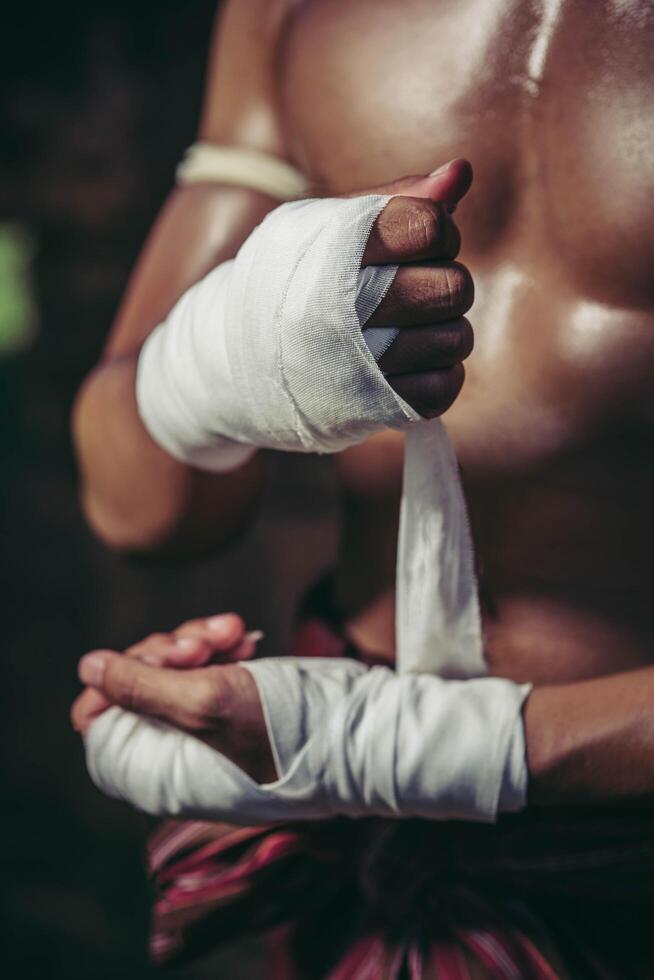 The boxer sat on the stone, tied the tape around his hand, preparing to fight. photo