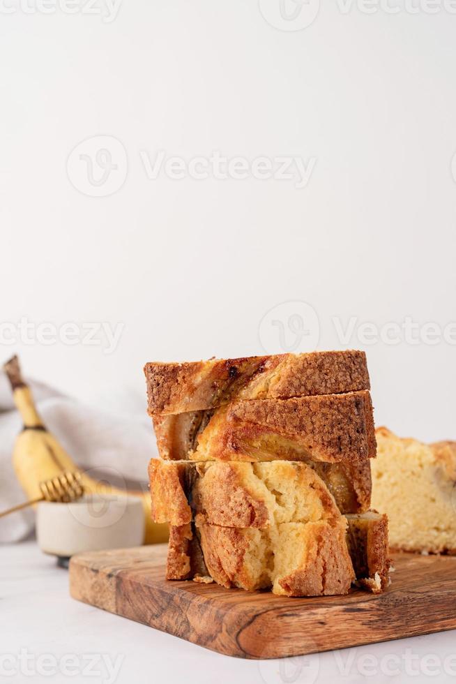 Vista frontal del pan de plátano en rodajas sobre fondo de hormigón claro, trozos de pastel apilados foto