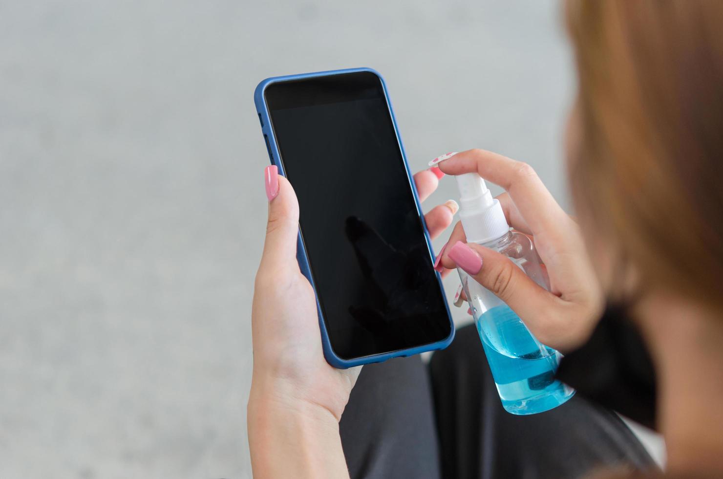 Wipe and disinfect your mobile phone with alcohol. concept of health care to prevent disease.Woman holding smart phone. photo