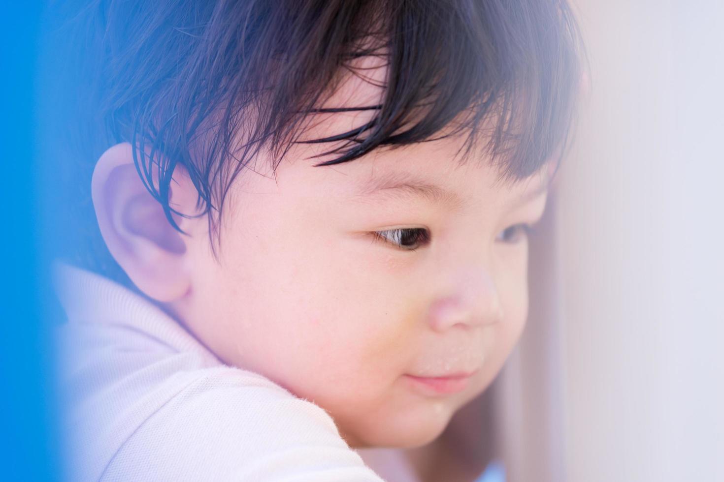 Boy aged 1-2 years sweet smile. Blur some objects in front view face. Portrait child playing in playground. Baby sweating and hot. photo