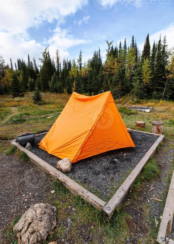 Orange tent camping on campsite in autumn forest at provincial park photo