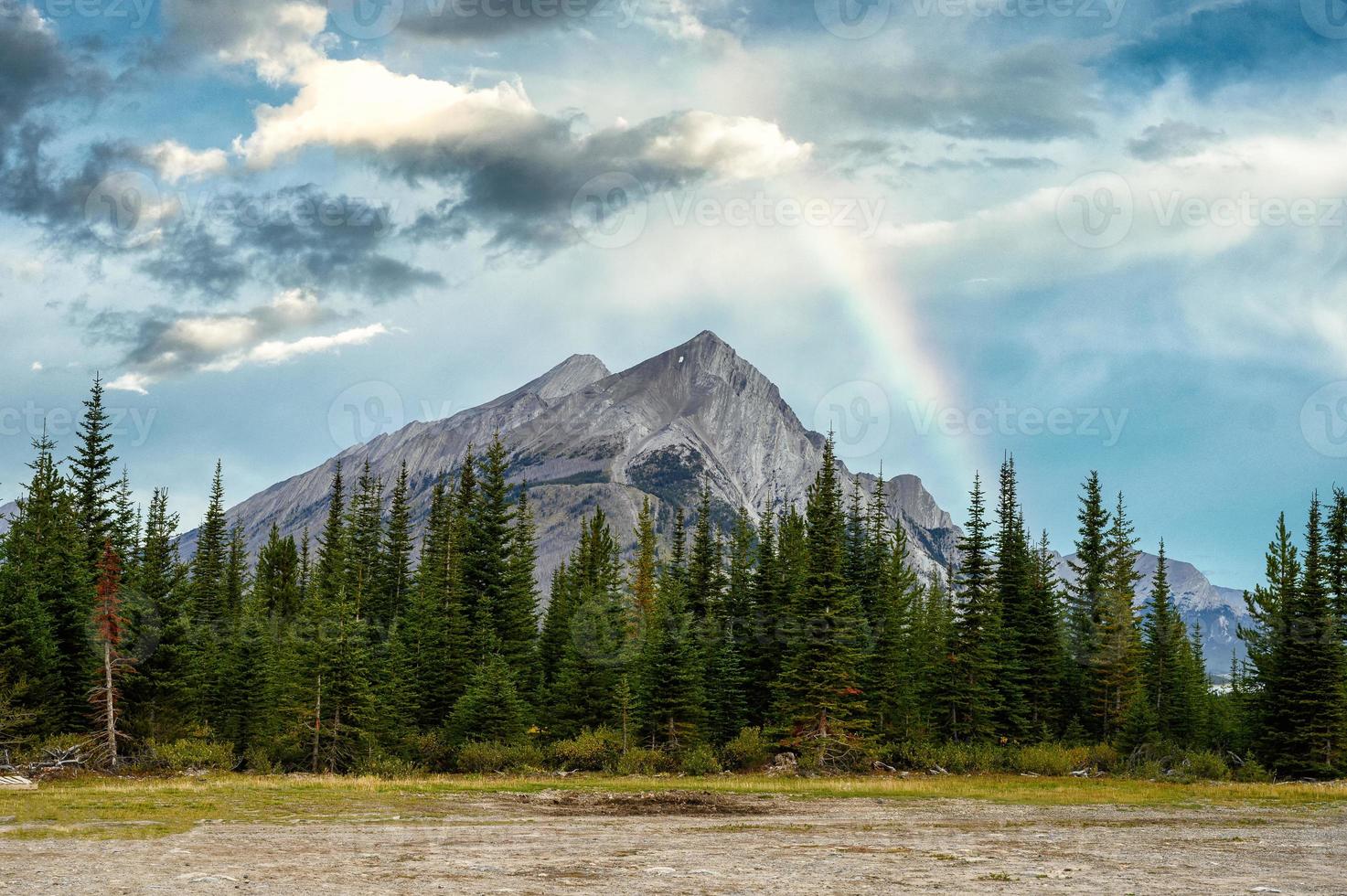 Monte rundle con pinos y arco iris en el cielo azul foto