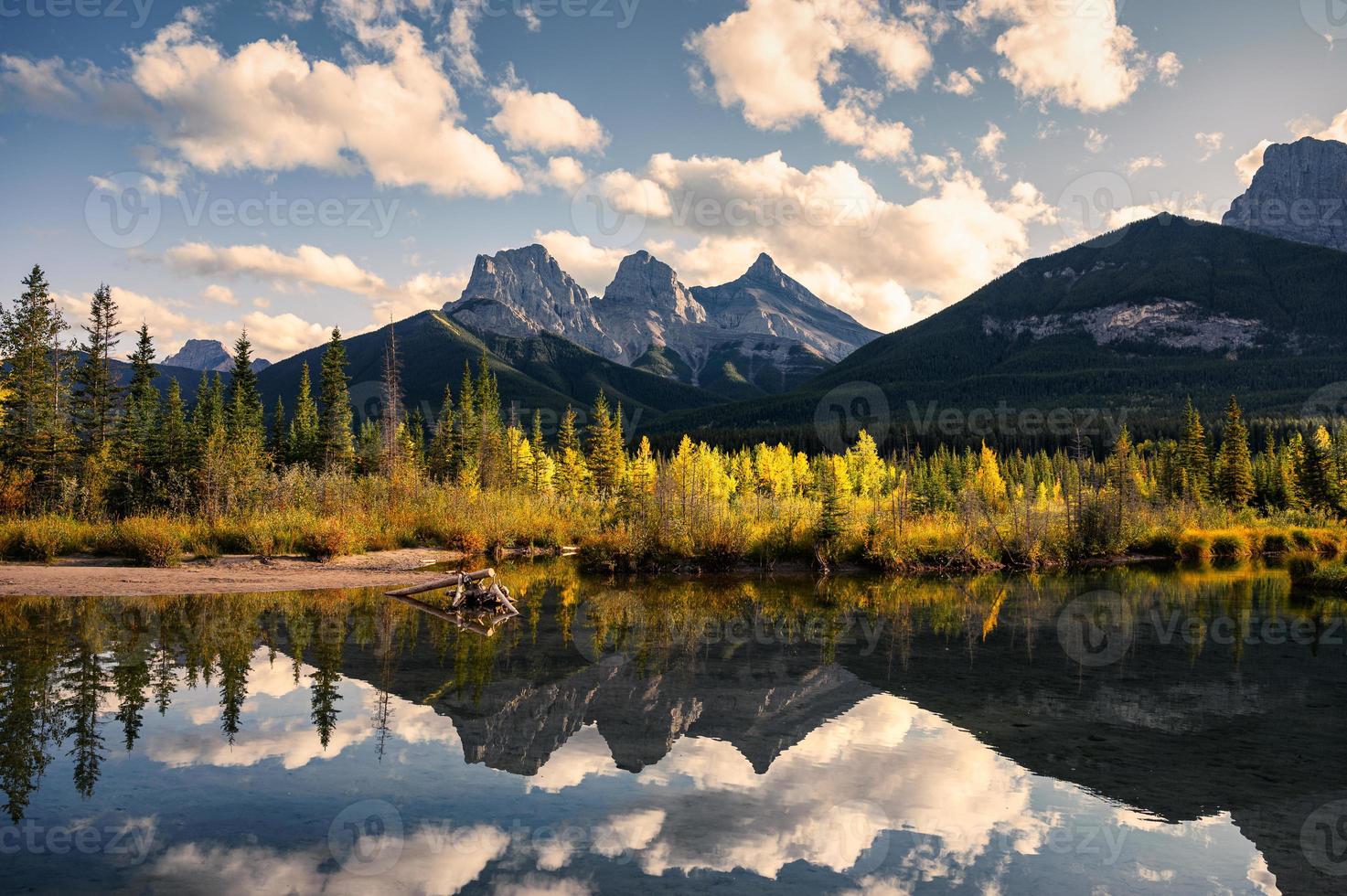 El paisaje de la montaña de las tres hermanas con la reflexión del bosque otoñal sobre el estanque en Canmore en el Parque Nacional Banff foto