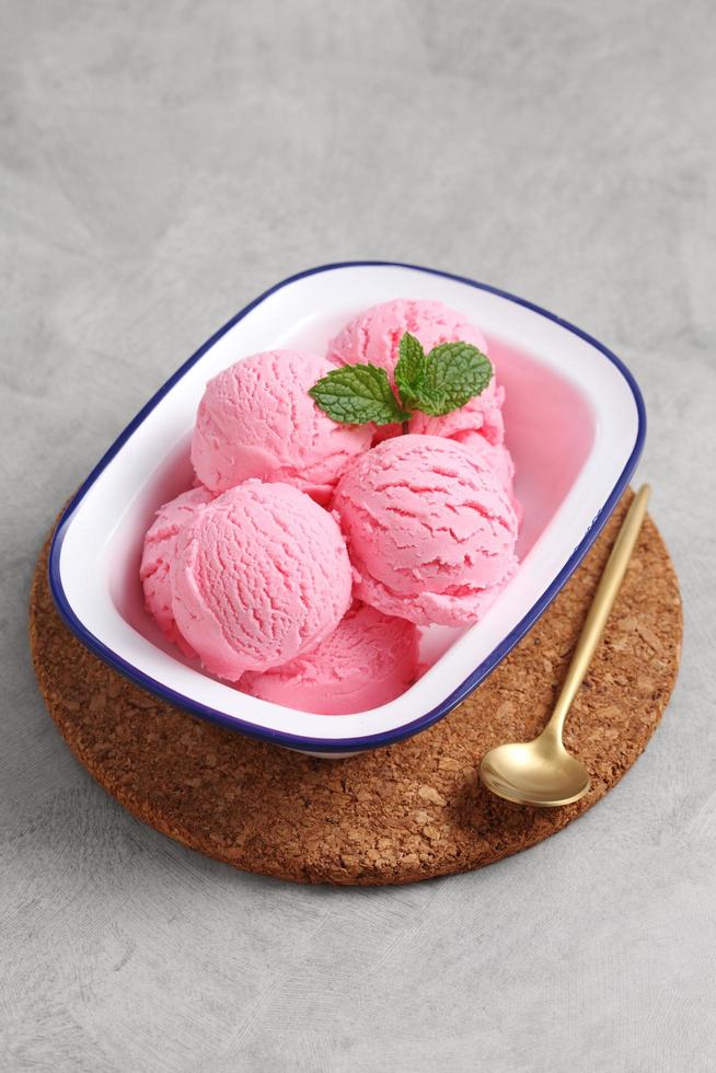 Helado de fresa en un tazón blanco sobre la tabla de cortar foto