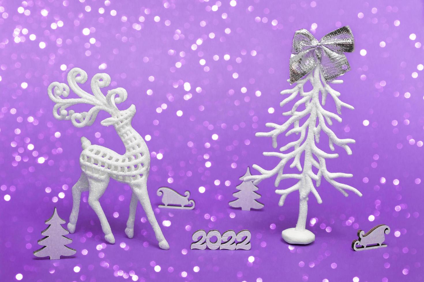 Merry Christmas and Happy New Year. Festive poster with a Christmas tree, a deer, a sleigh on a purple background with lights. New year 2022 copy space close up photo