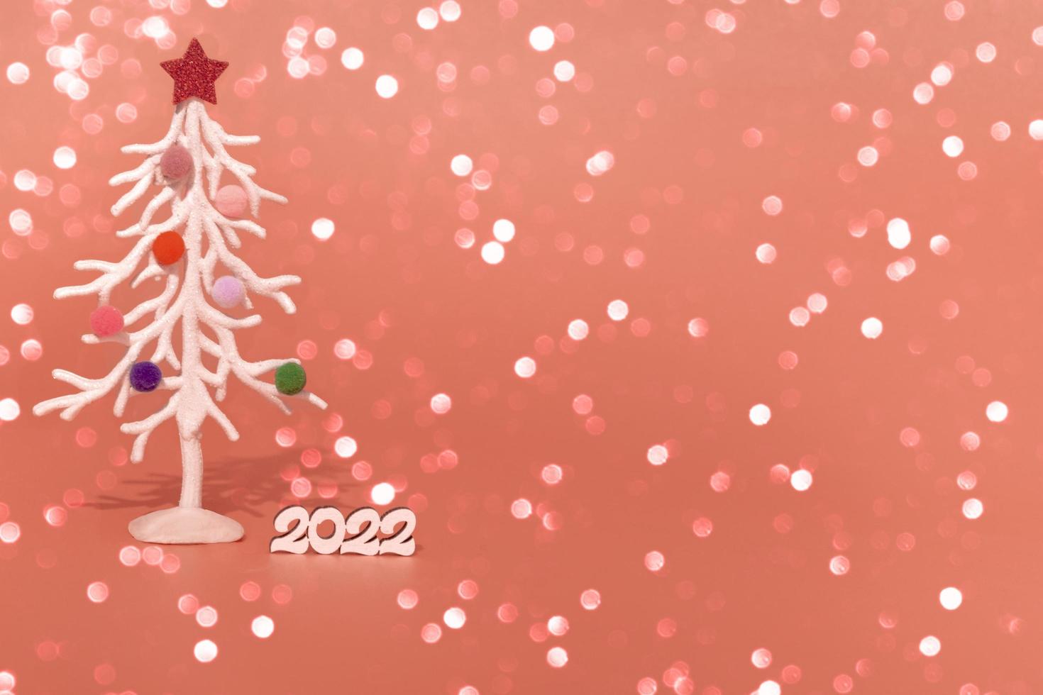 Christmas card. Against the background of Christmas lights, a white Christmas tree in multi-colored fur toys with the numbers 2022. copy space photo