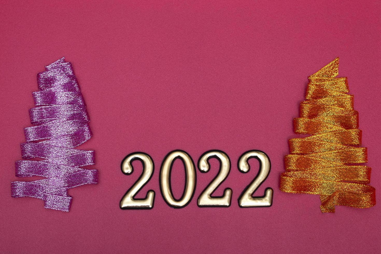 Christmas concept. Purple and gold Christmas tree made of ribbons and gold numbers on a pink background. Template for postcards, packaging. photo