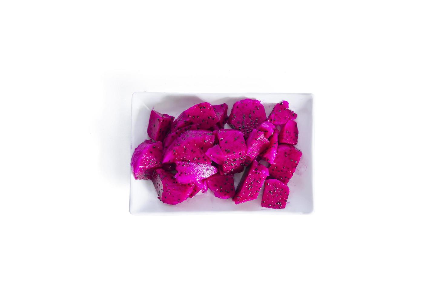 Dragon fruit cut into small pieces served on a white plate isolated on a white background. top view photo