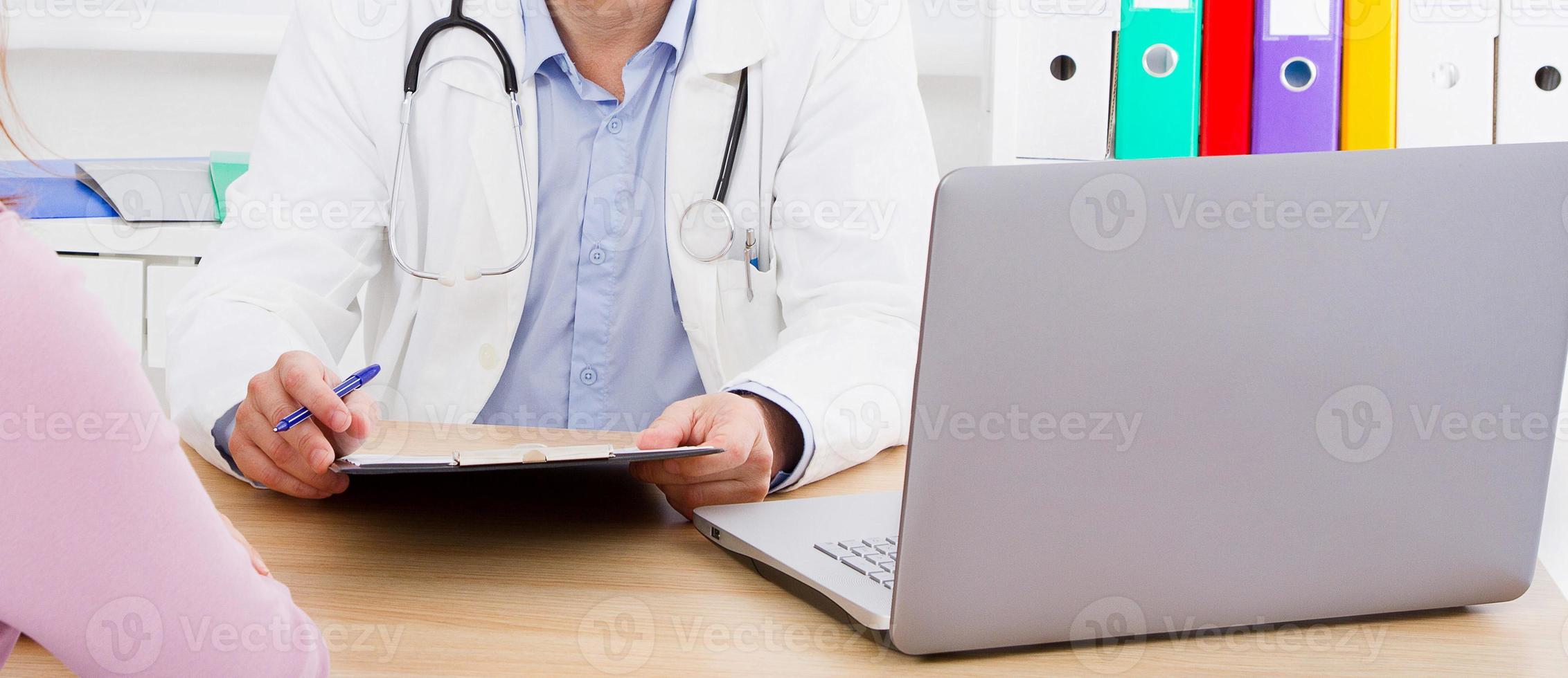 male doctor at the table attentively listening to patient complaints photo