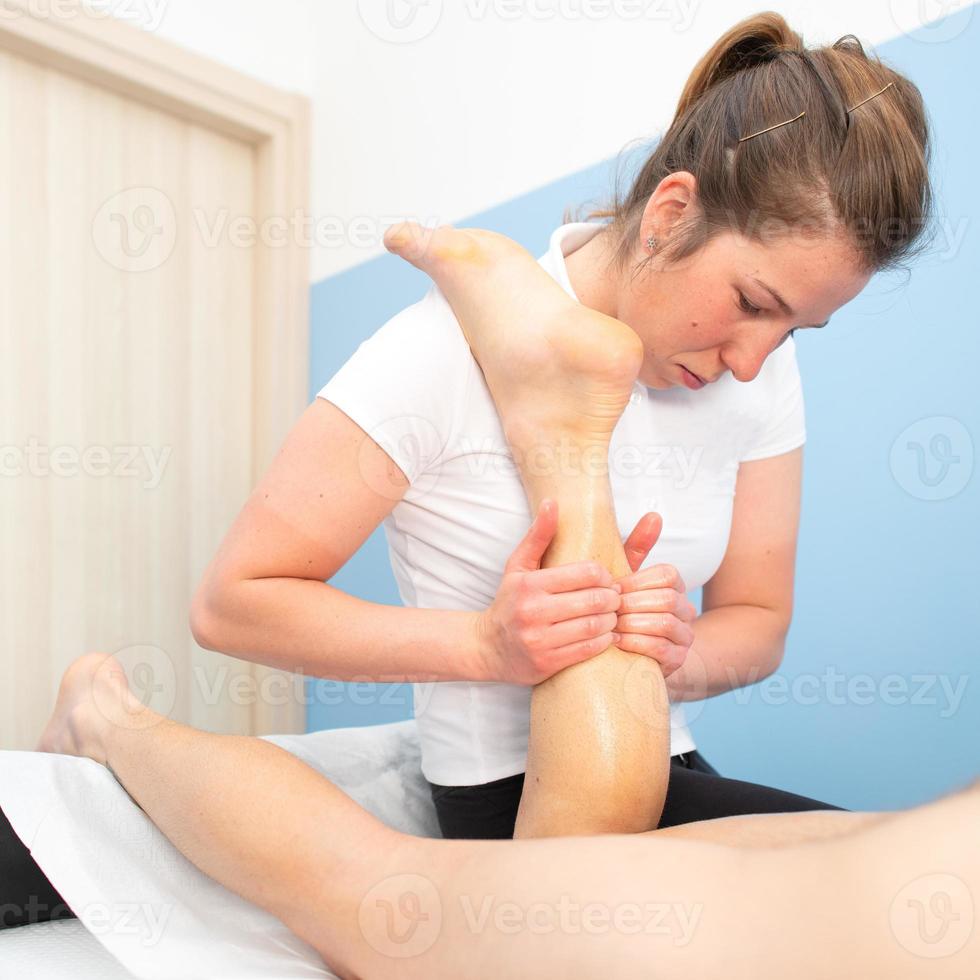 Hands of professional physiotherapist on calf of athlete photo