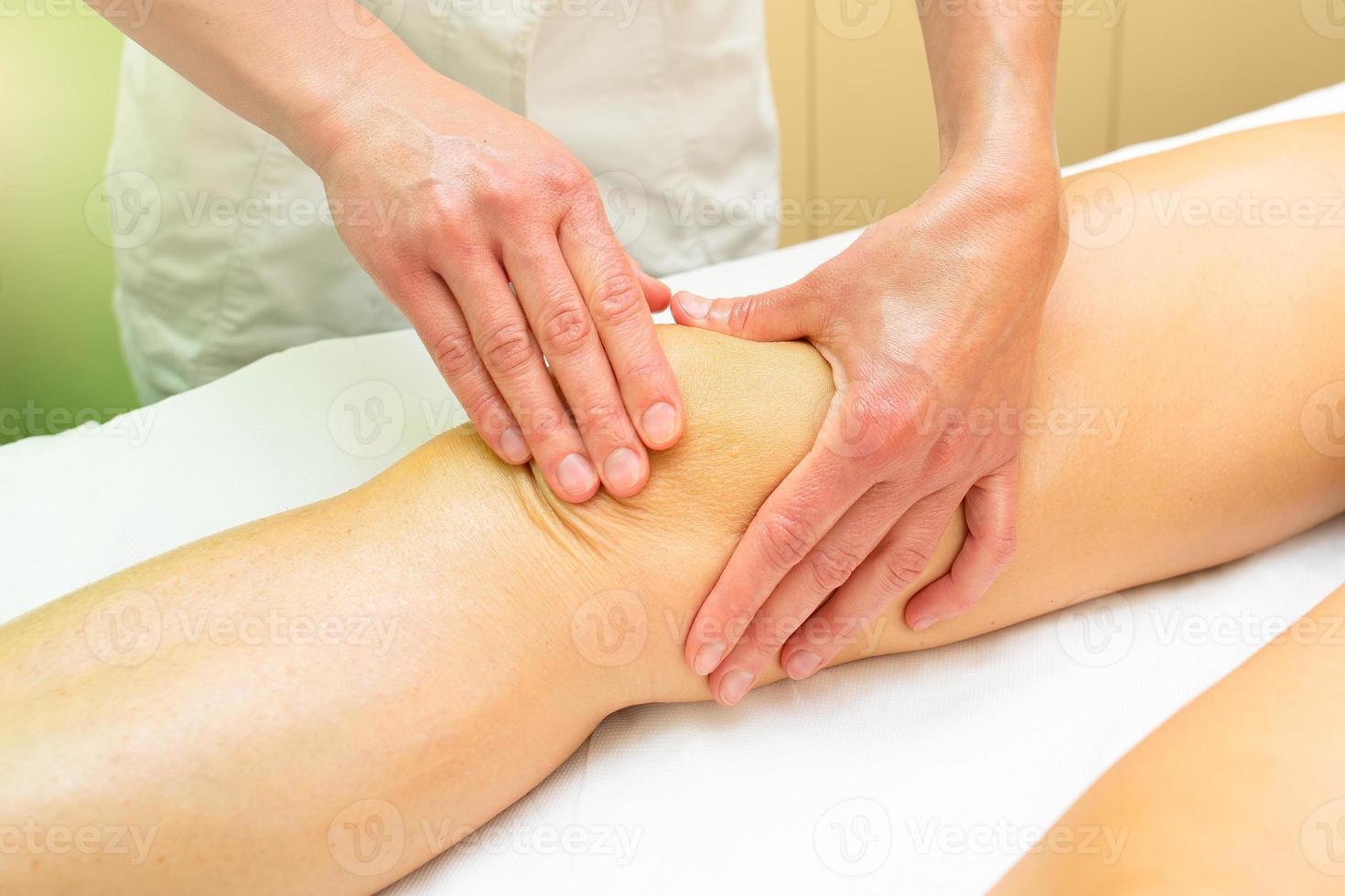 Esteticista practica un relajante masaje de rodilla. foto