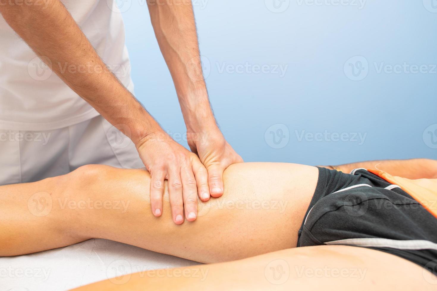 Quadriceps massage to an athlete by a physiotherapist photo