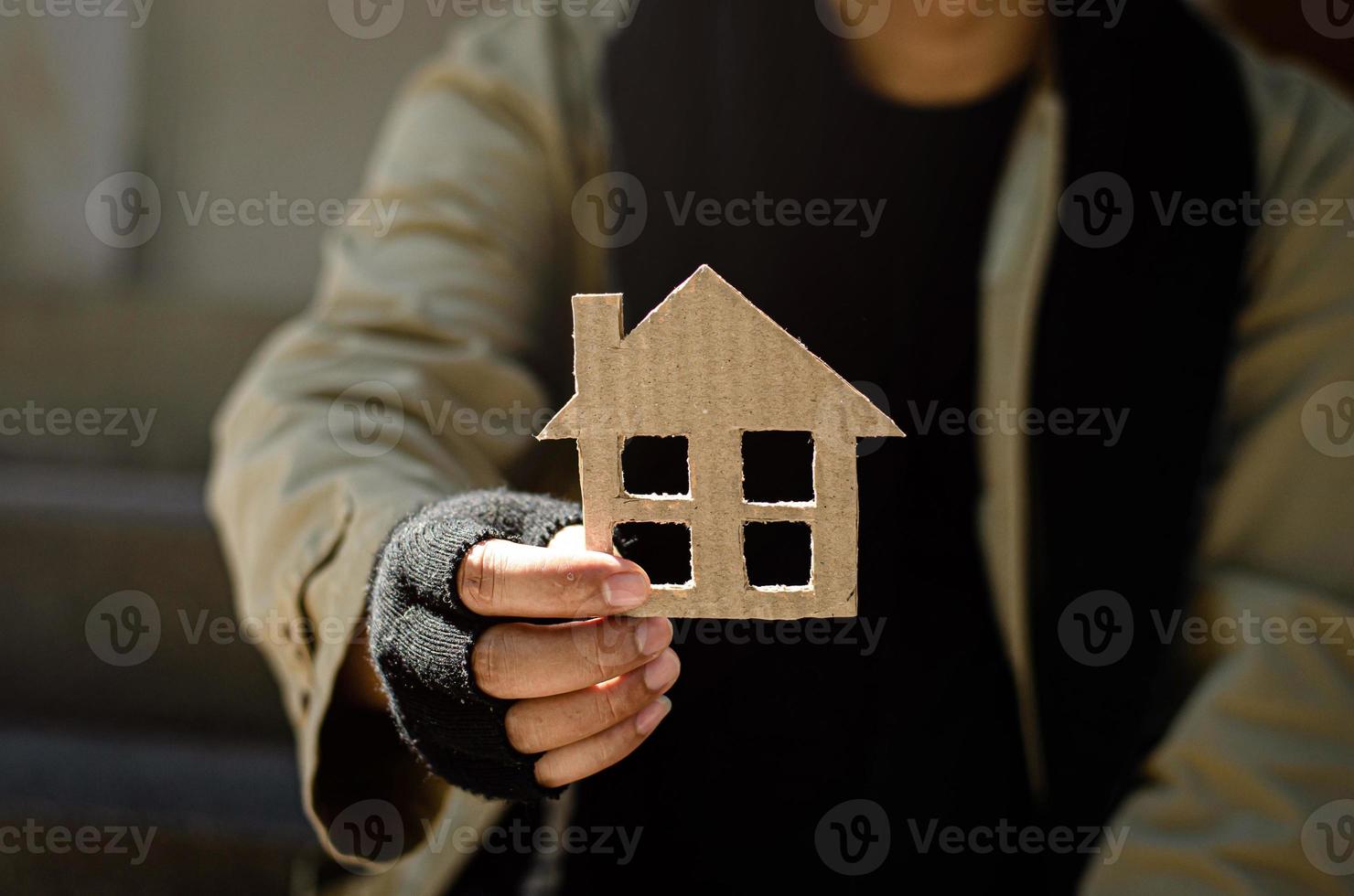 un vagabundo que está desanimado, desesperado, yerra de la vida. Sin hogar, un mendigo sin hogar entregó una foto de una casa de papel para ayudar con las donaciones.