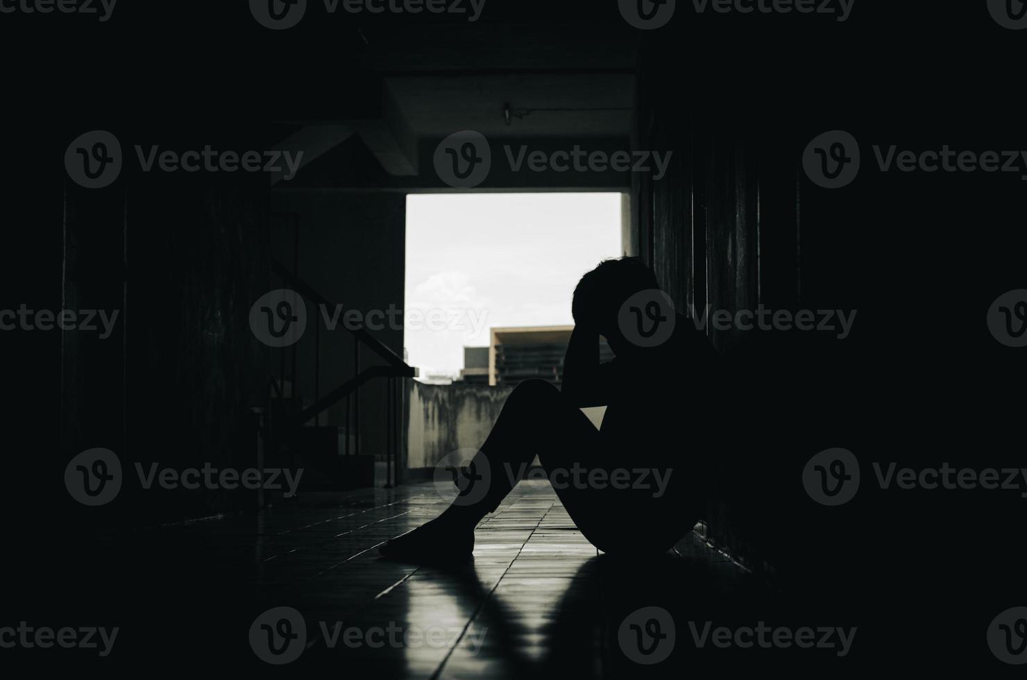 A young man who is exhausted from life's problems. with a feeling of depression and stress sitting on a dark corridor Bad and unhappy life concept photo