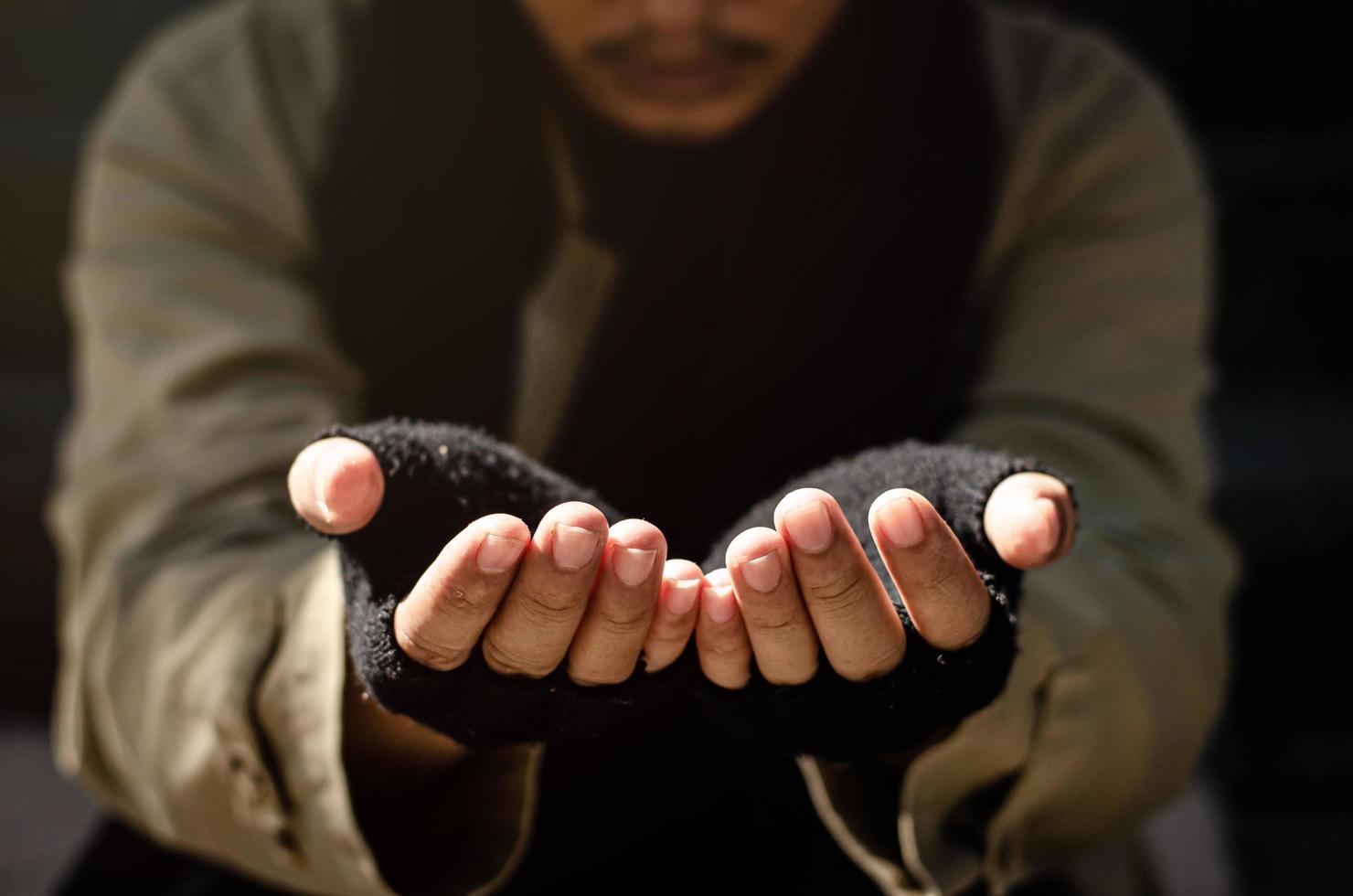 A homeless man begging for help. Ask for a coin of human mercy on a wooden floor in a public walkway. poor homeless people in the city social problems Finance and housing photo