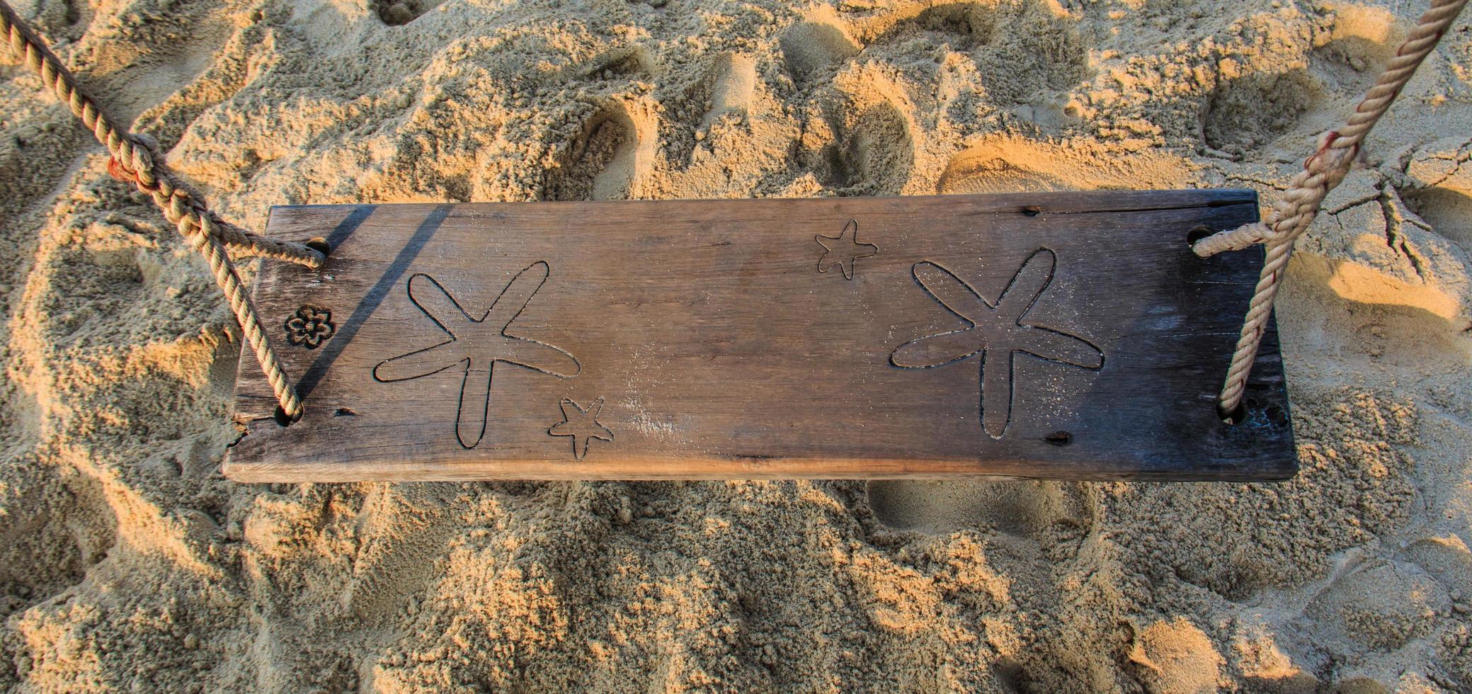 Wood swing on sand beach photo