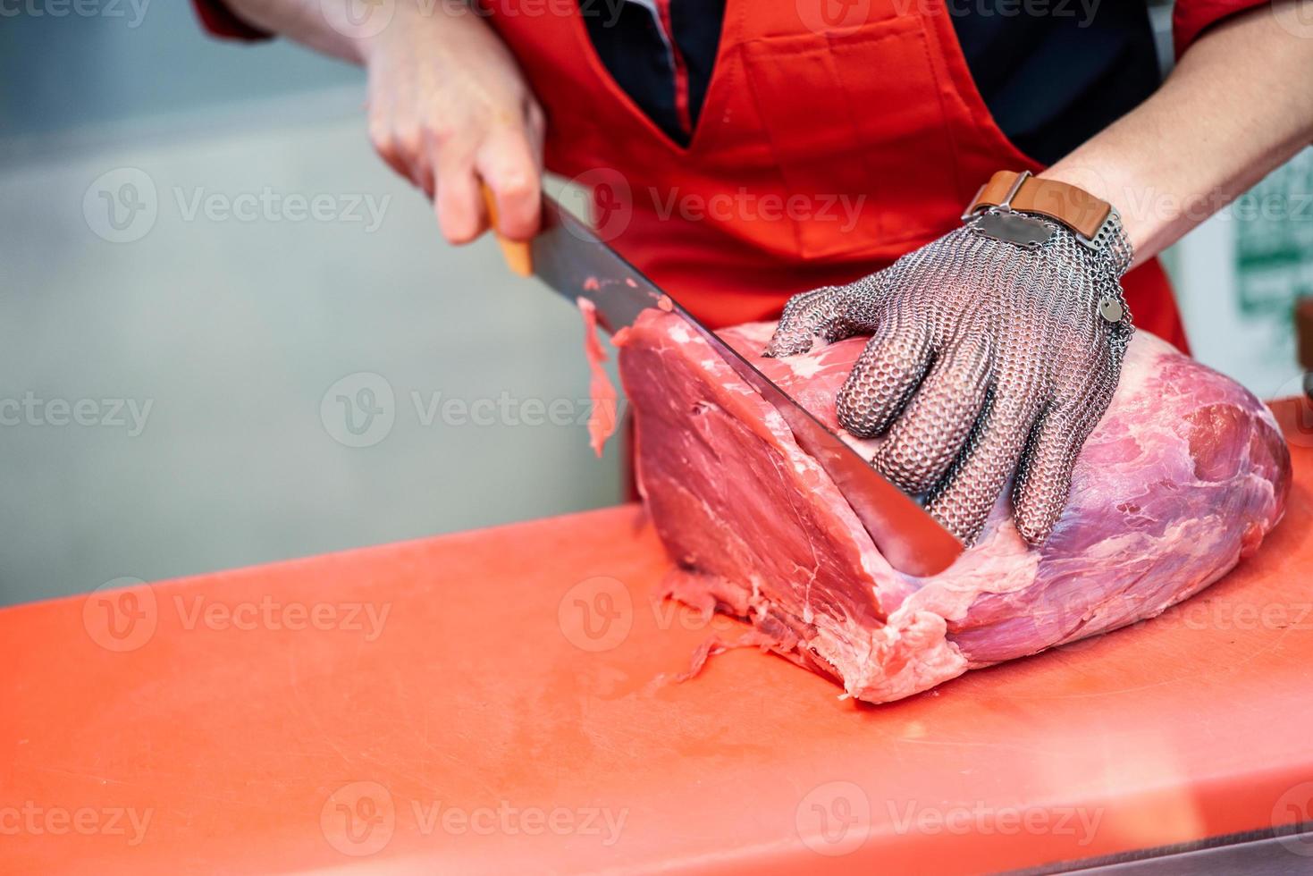 Woman cutting fresh meat in a butcher shop with metal safety mesh glove photo