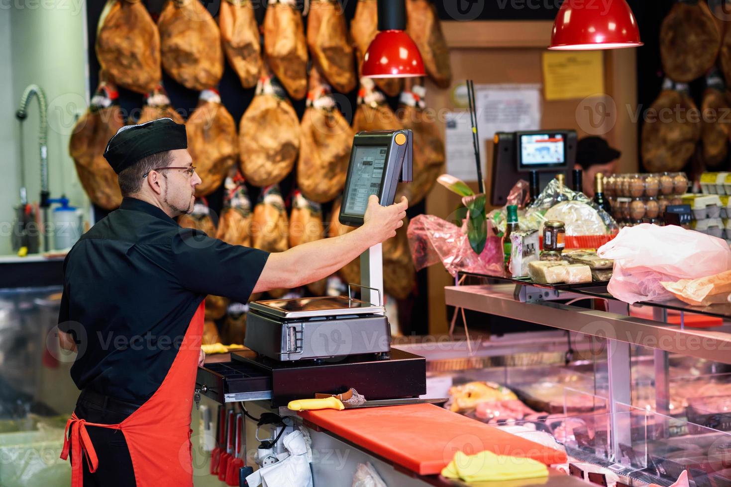 Butcher in a butcher's shop weighing the meat and charging photo