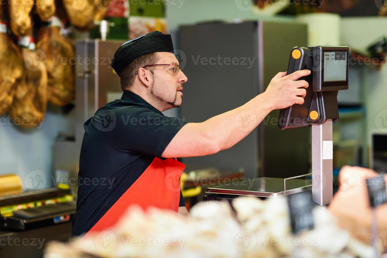 Butcher in a butcher's shop weighing the meat and charging photo