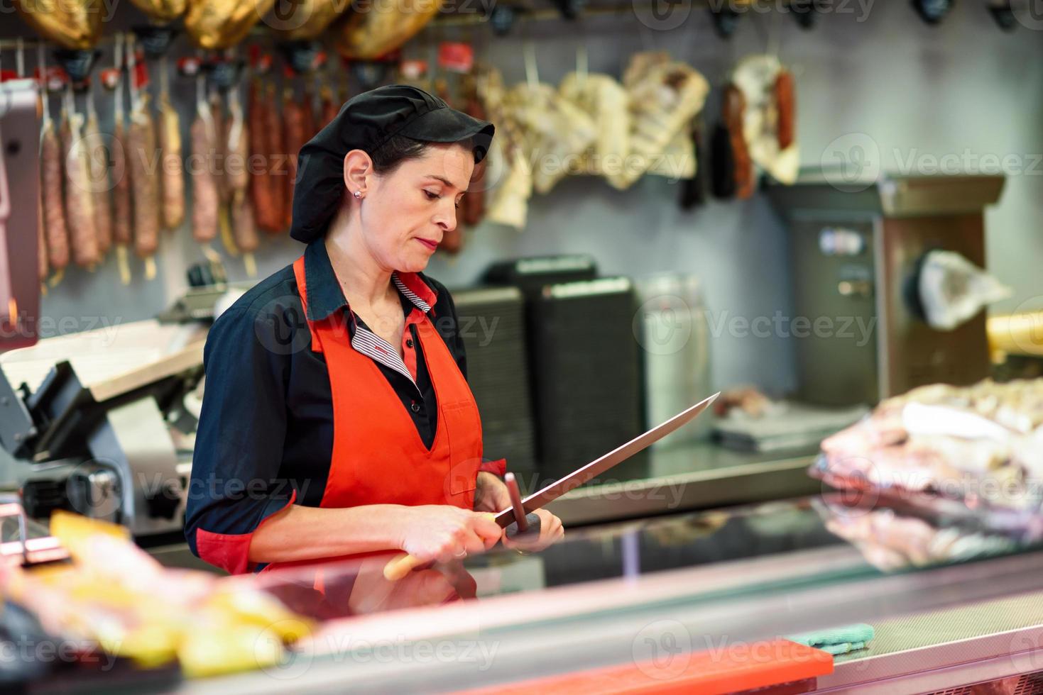 Carnicero afilando un cuchillo en una carnicería foto