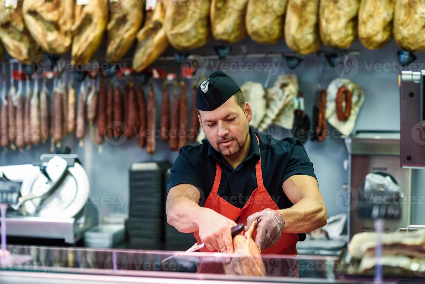 Carnicero deshuesando un jamón en una carnicería moderna foto