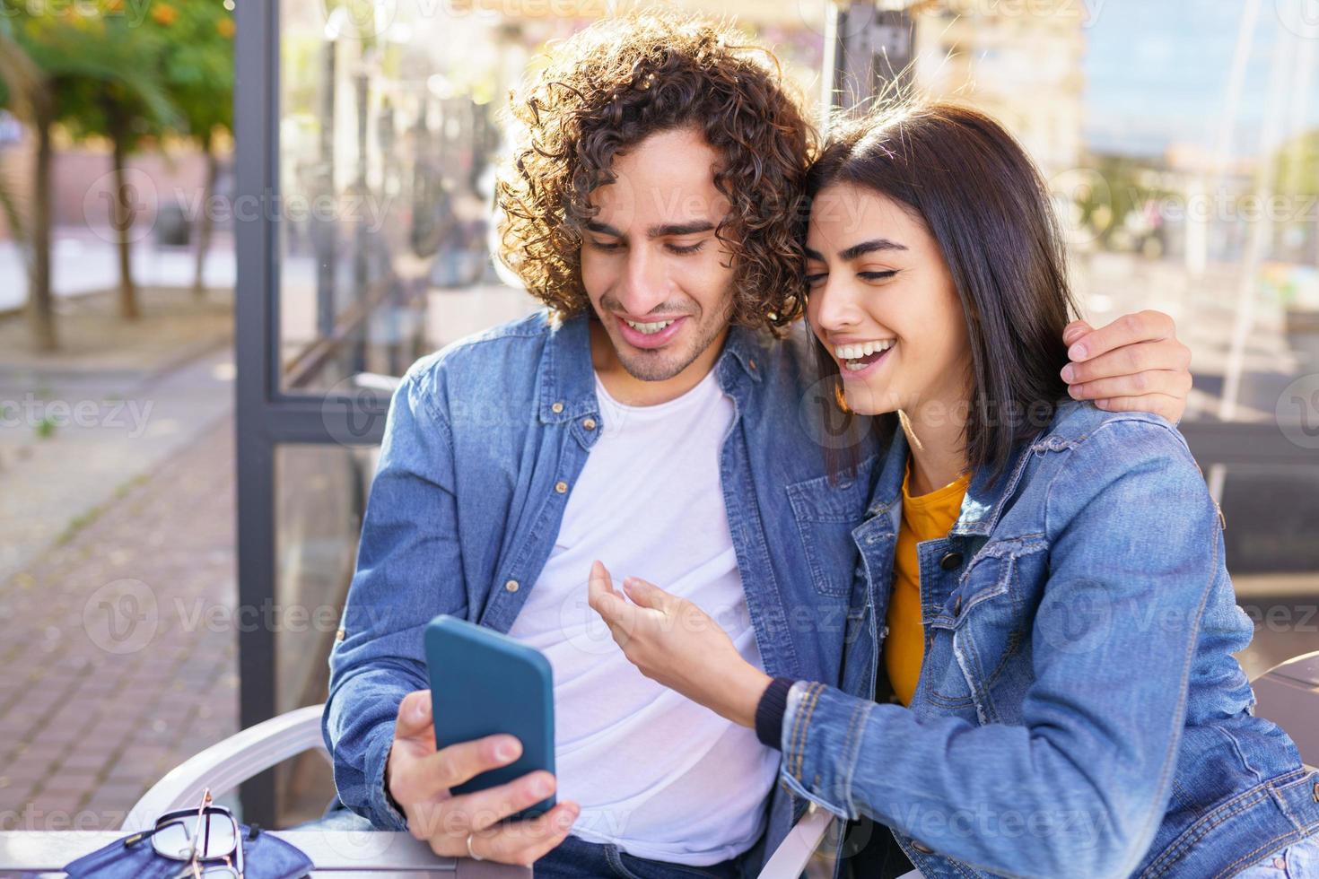 Pareja árabe mirando fotografías tomadas con su teléfono inteligente al aire libre foto