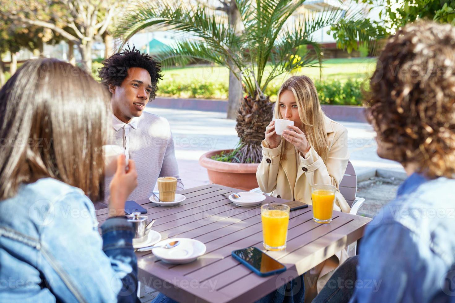 Grupo multiétnico de amigos tomando una copa juntos en un bar al aire libre. foto