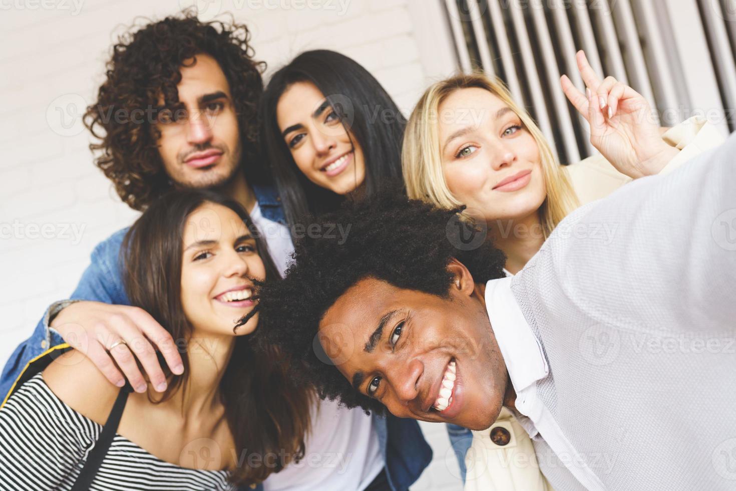 Grupo multiétnico de amigos tomando un selfie juntos mientras se divierten al aire libre. foto