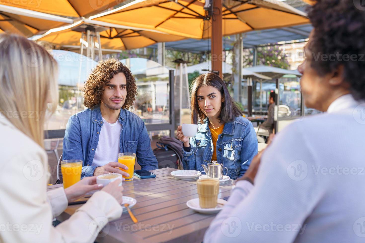 Grupo multiétnico de amigos tomando una copa juntos en un bar al aire libre. foto