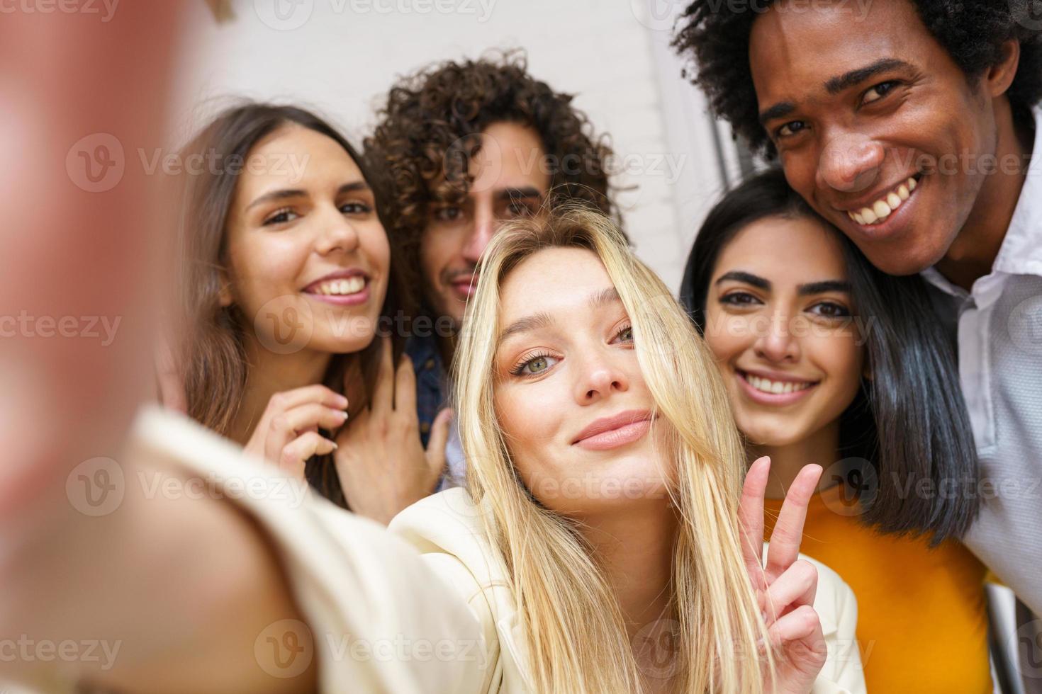 Grupo multiétnico de amigos tomando un selfie juntos mientras se divierten al aire libre. foto