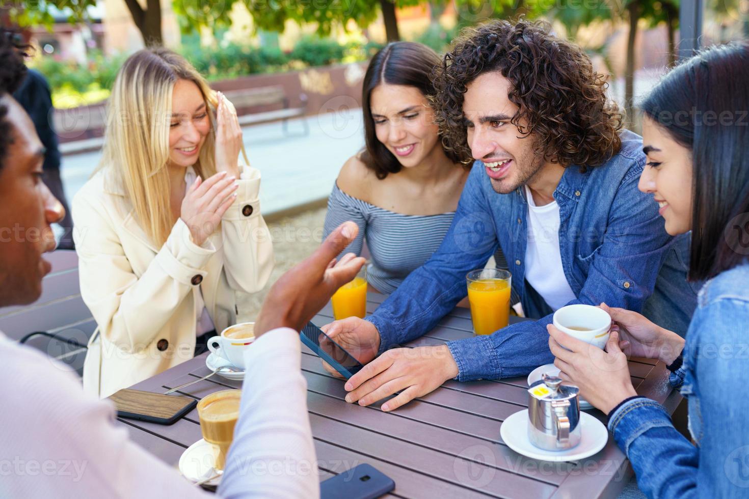 Multi-ethnic group of friends having a drink together in an outdoor bar ...