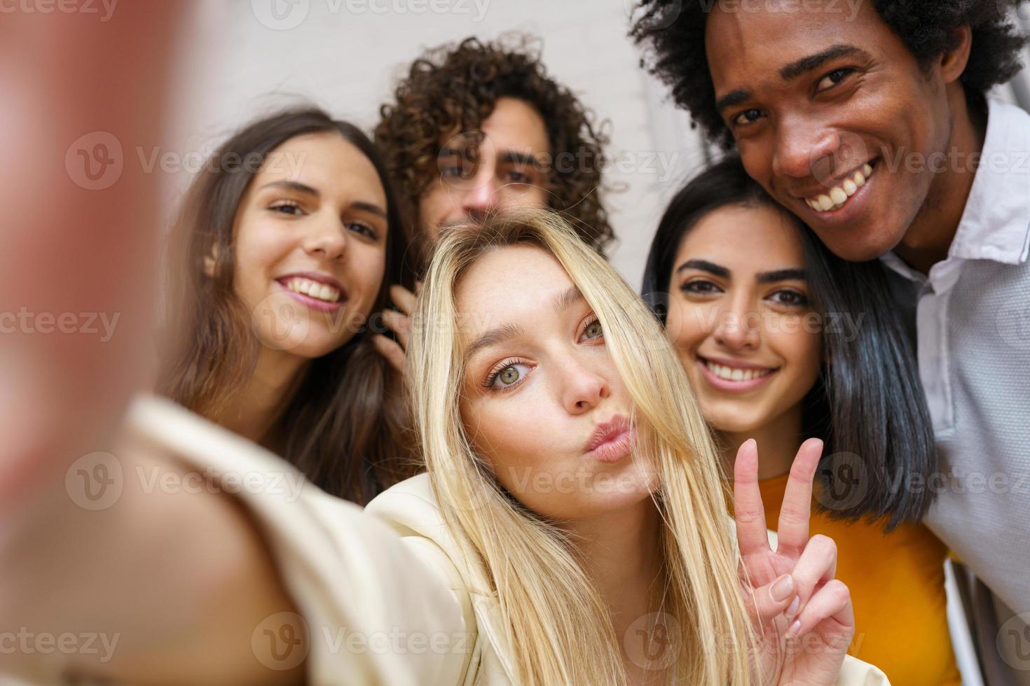 Multi-ethnic group of friends taking a selfie together while having fun outdoors. photo