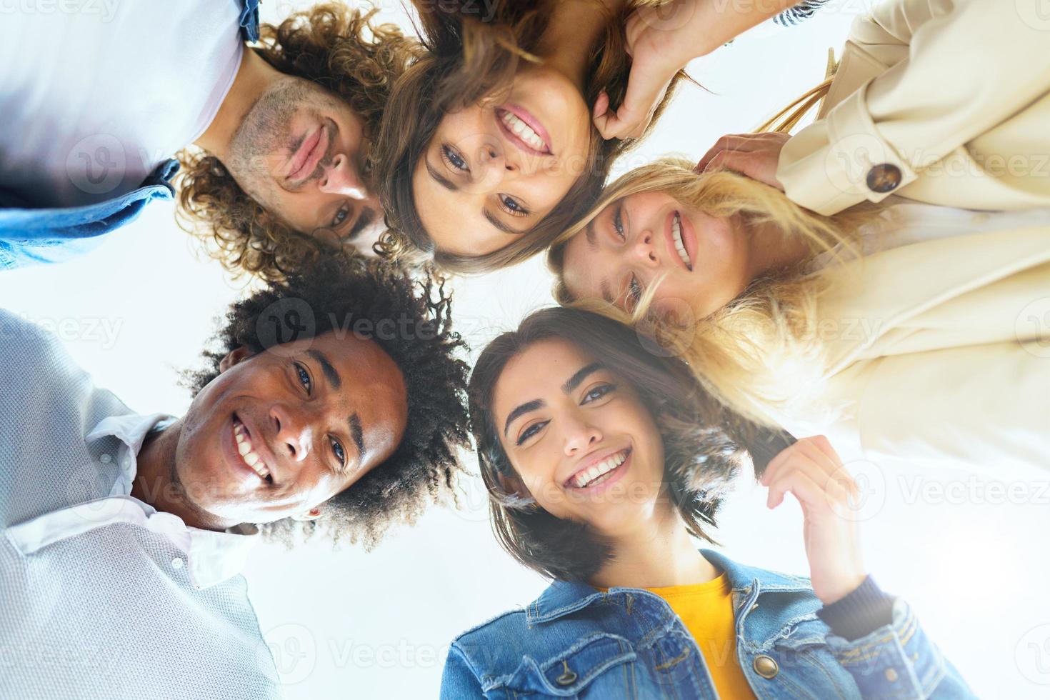 grupo multiétnico de amigos con sus cabezas juntas en un círculo. foto