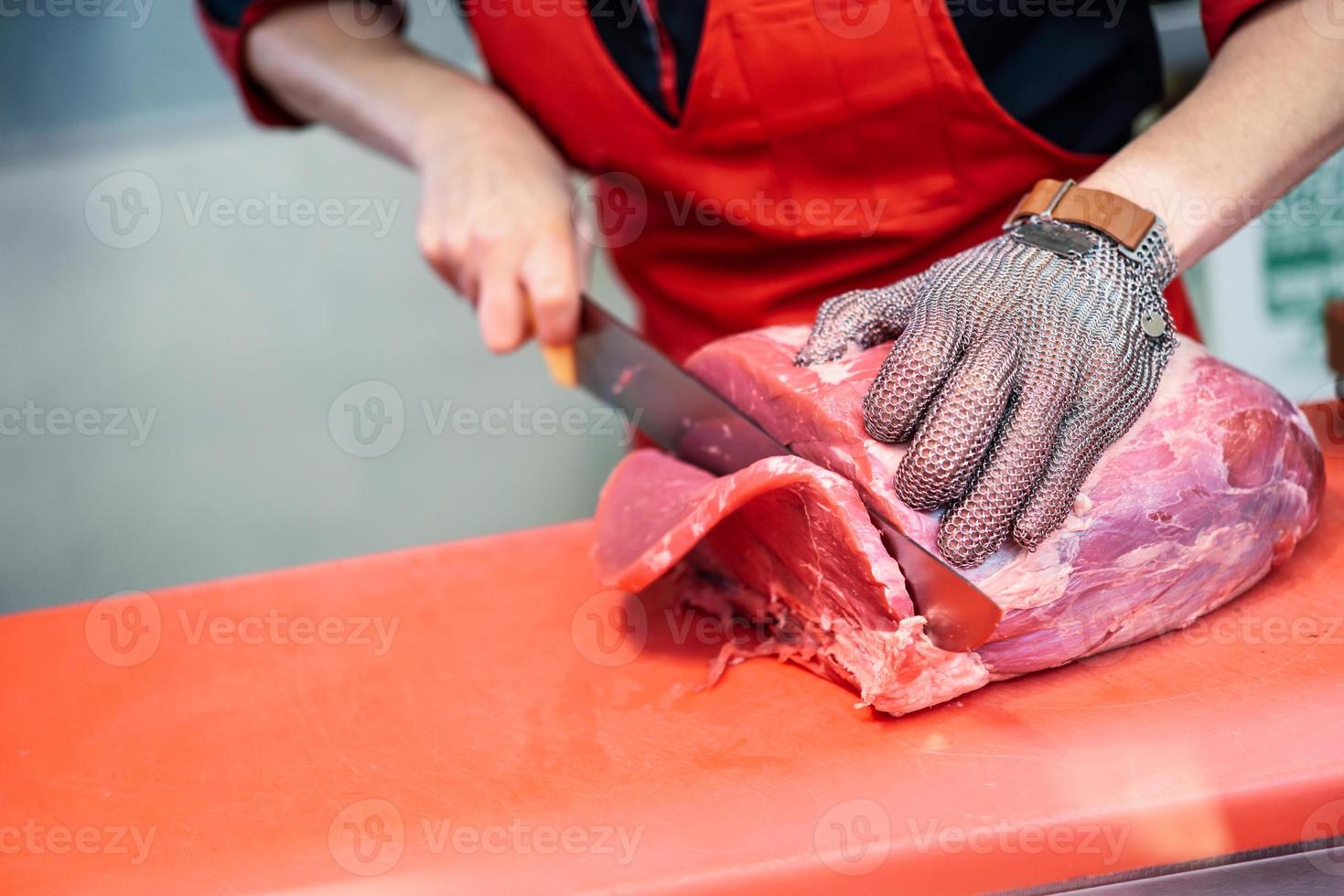 Mujer cortando carne fresca en una carnicería con guante de malla de seguridad metálica foto