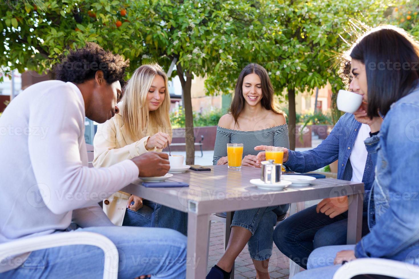 Multi-ethnic group of friends having a drink together in an outdoor bar. photo