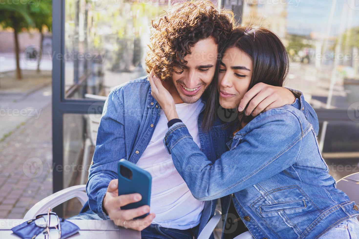 Arab couple looking at pictures taken with their smartphone outdoors photo