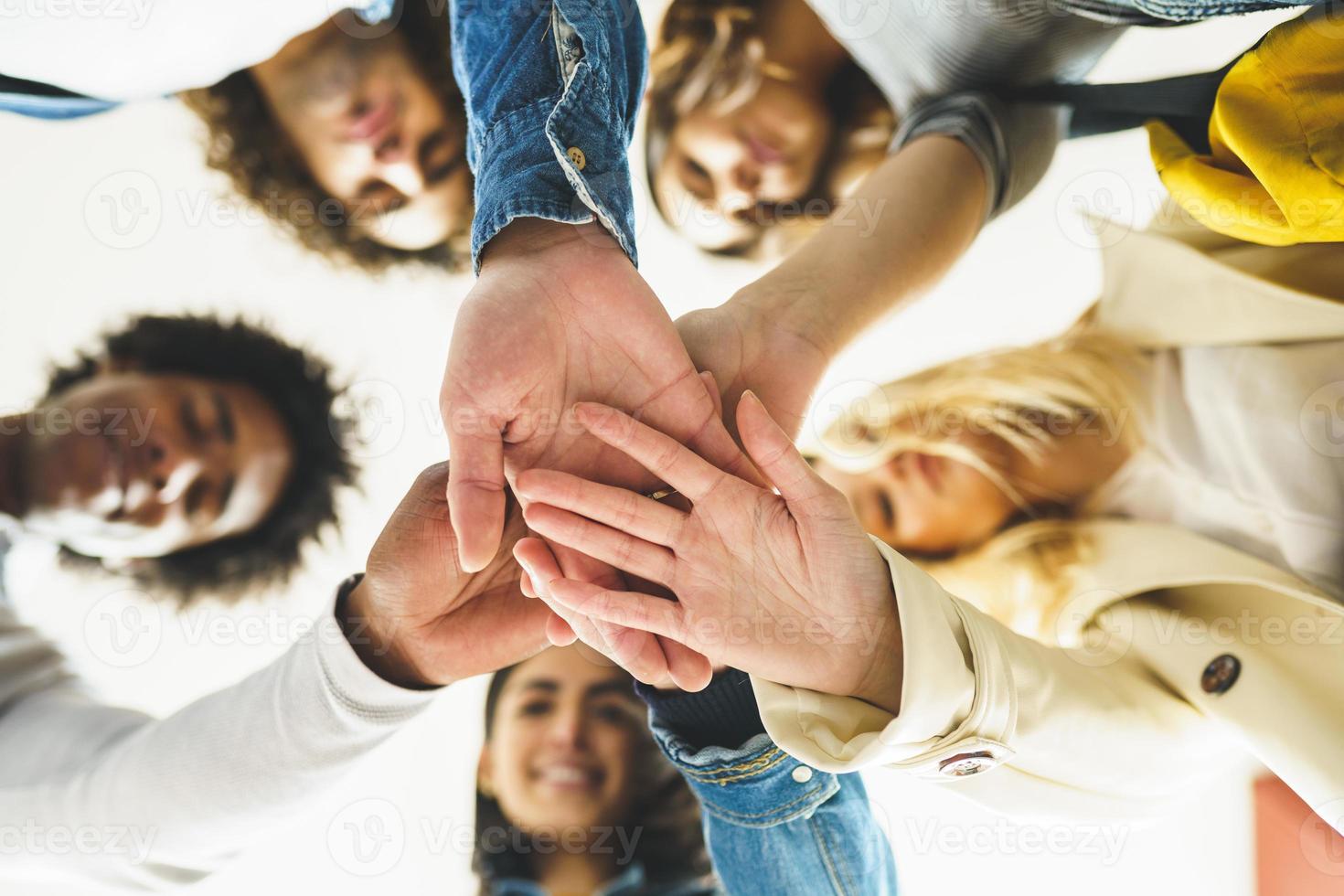 Hands of a multi-ethnic group of friends joined together as a sign of support and teamwork. photo