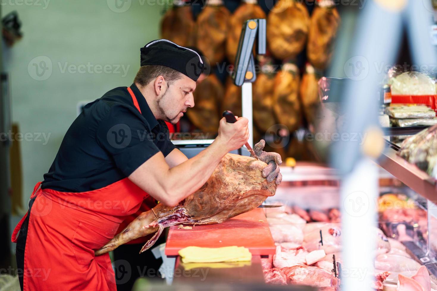 Carnicero deshuesando un jamón en una carnicería moderna foto