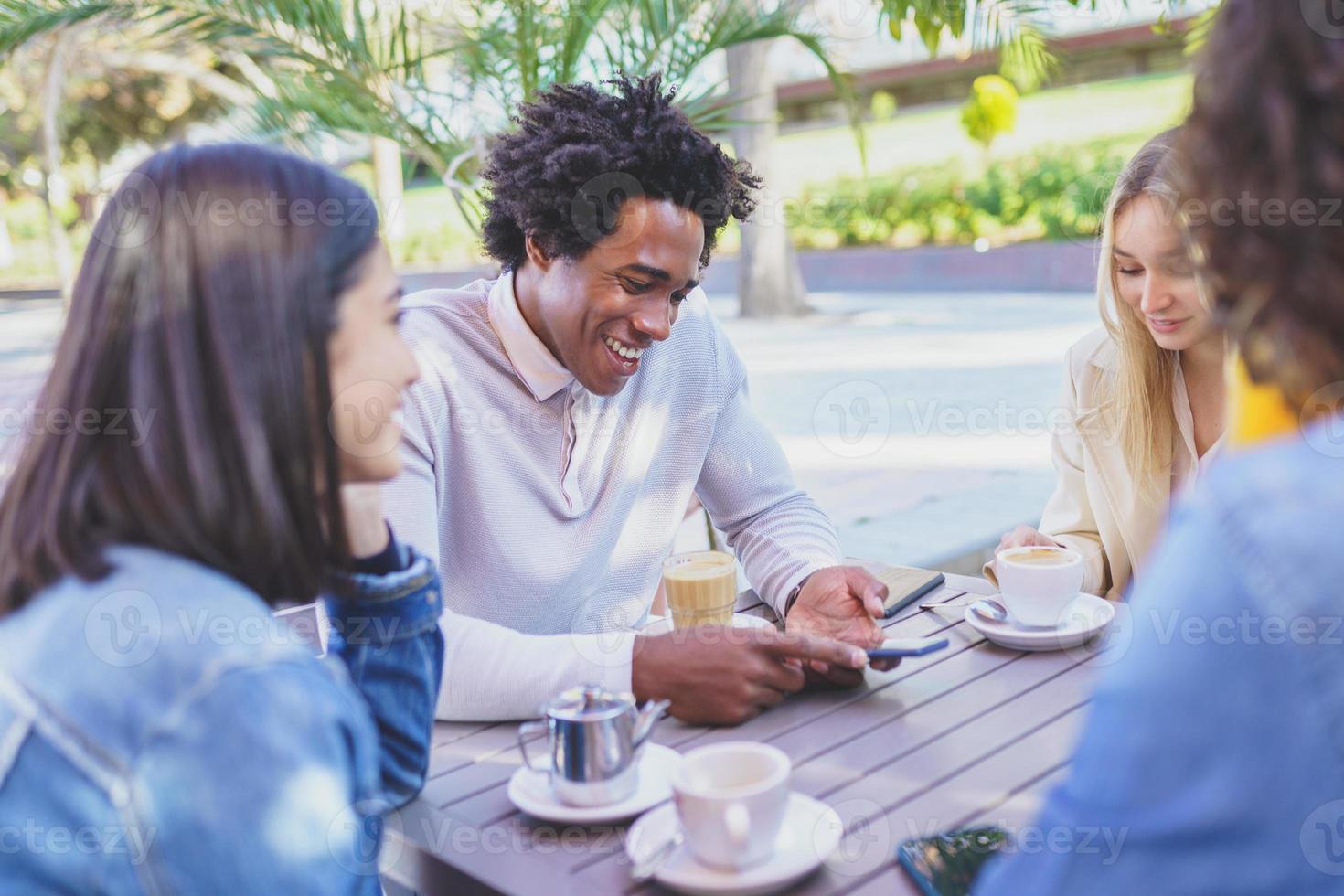 Multi-ethnic group of friends having a drink together in an outdoor bar. photo