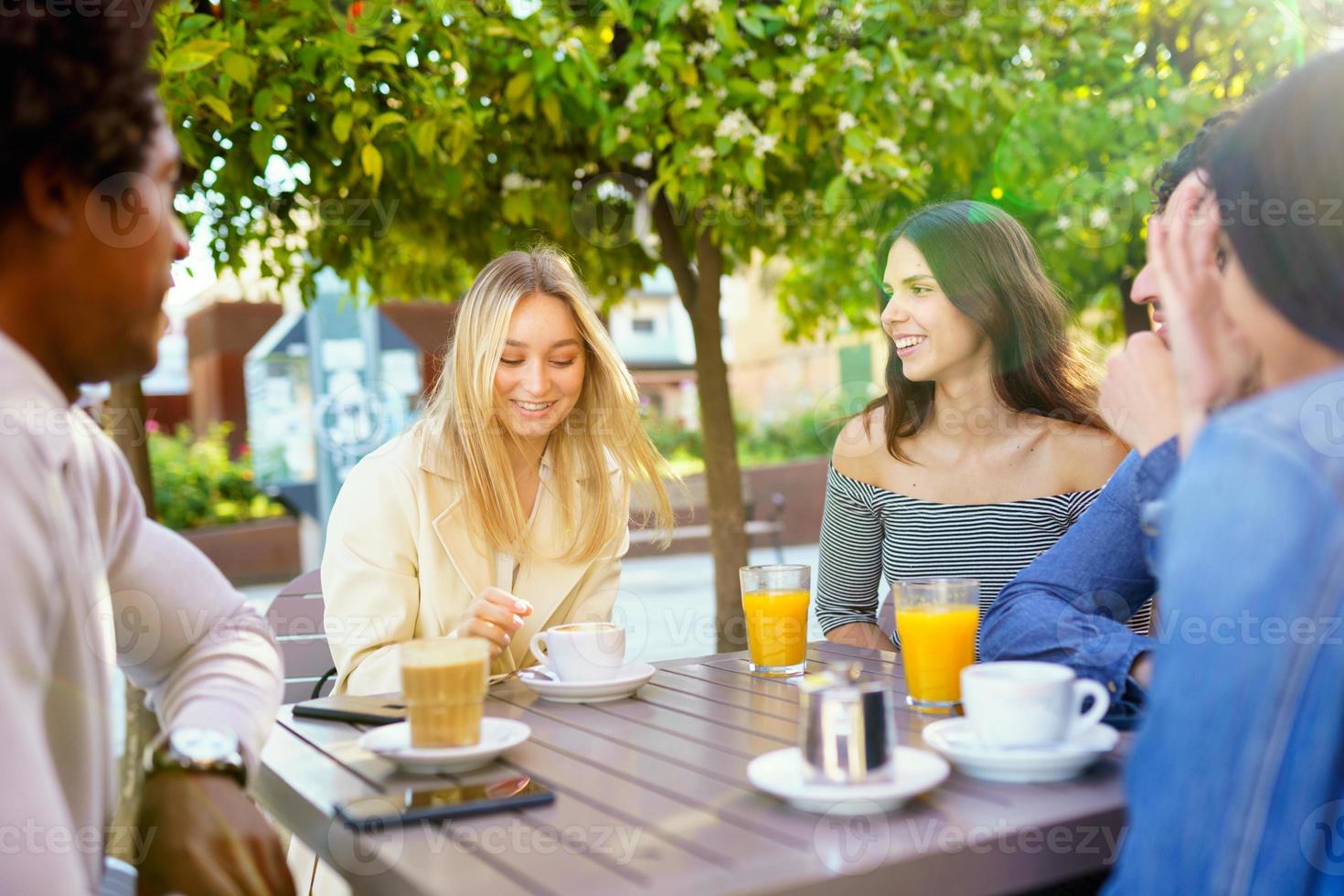 Multi-ethnic group of friends having a drink together in an outdoor bar. photo