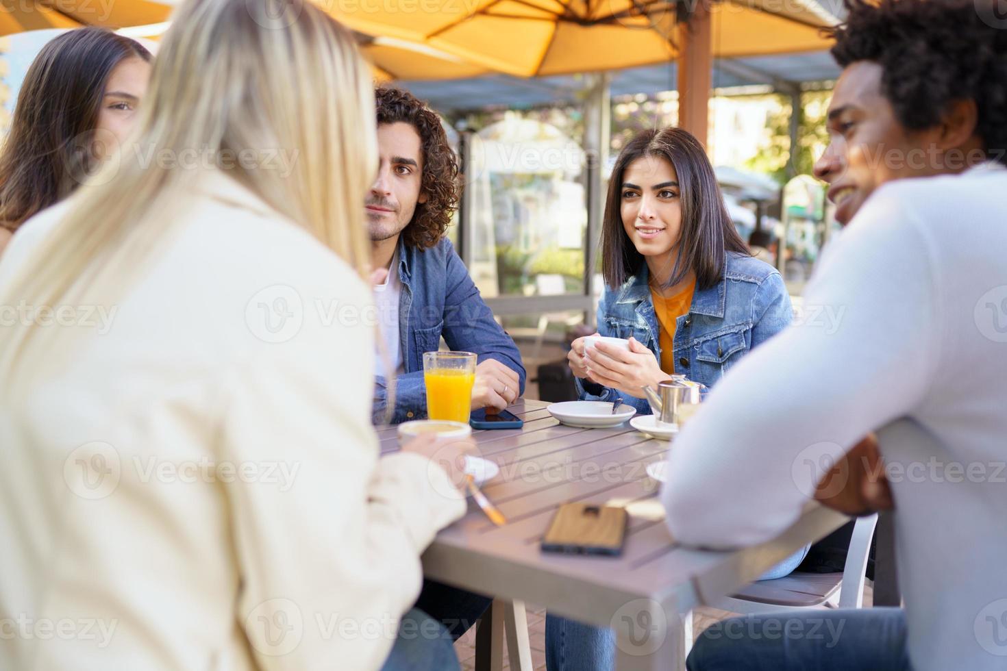 Multi-ethnic group of friends having a drink together in an outdoor bar. photo