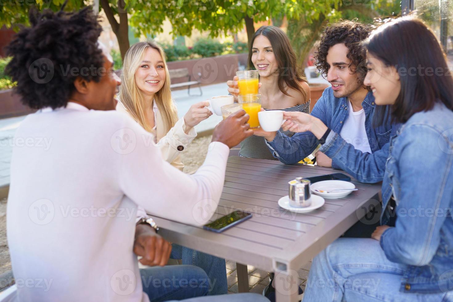 grupo multiétnico de amigos brindando con sus bebidas mientras toman una copa juntos. foto