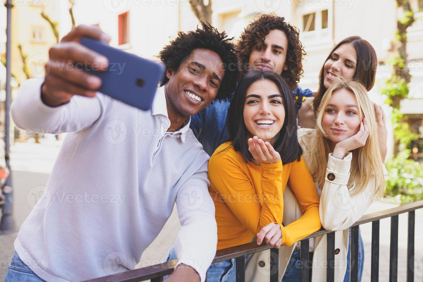 Hombre negro con cabello afro tomando un selfie de teléfono inteligente con su grupo multiétnico de amigos. foto