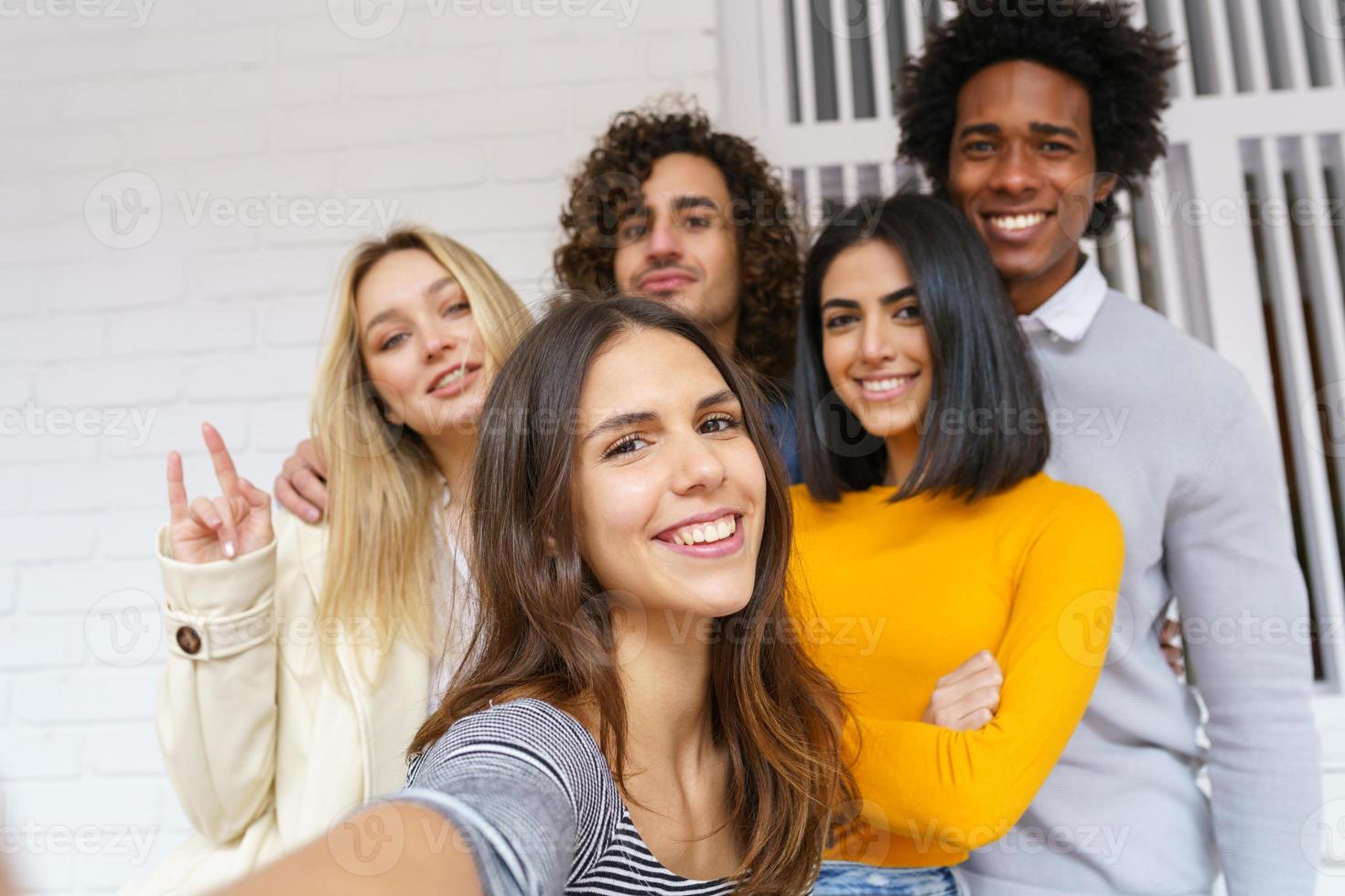 Grupo multiétnico de amigos tomando un selfie juntos mientras se divierten al aire libre. foto