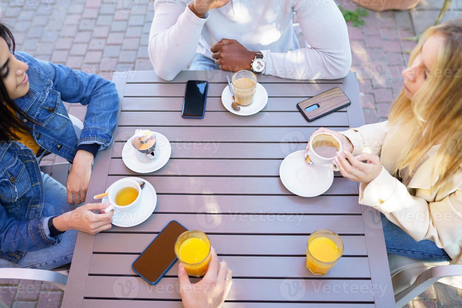 Top view of people drinking coffee, juice and tea sitting at the table on the terrace of a bar. photo