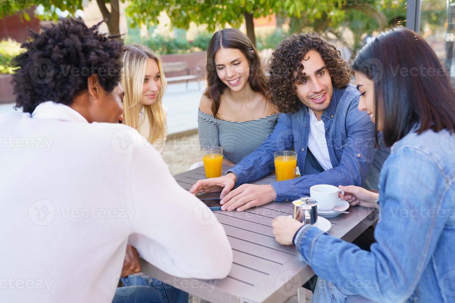 Multi-ethnic group of friends having a drink together in an outdoor bar. photo