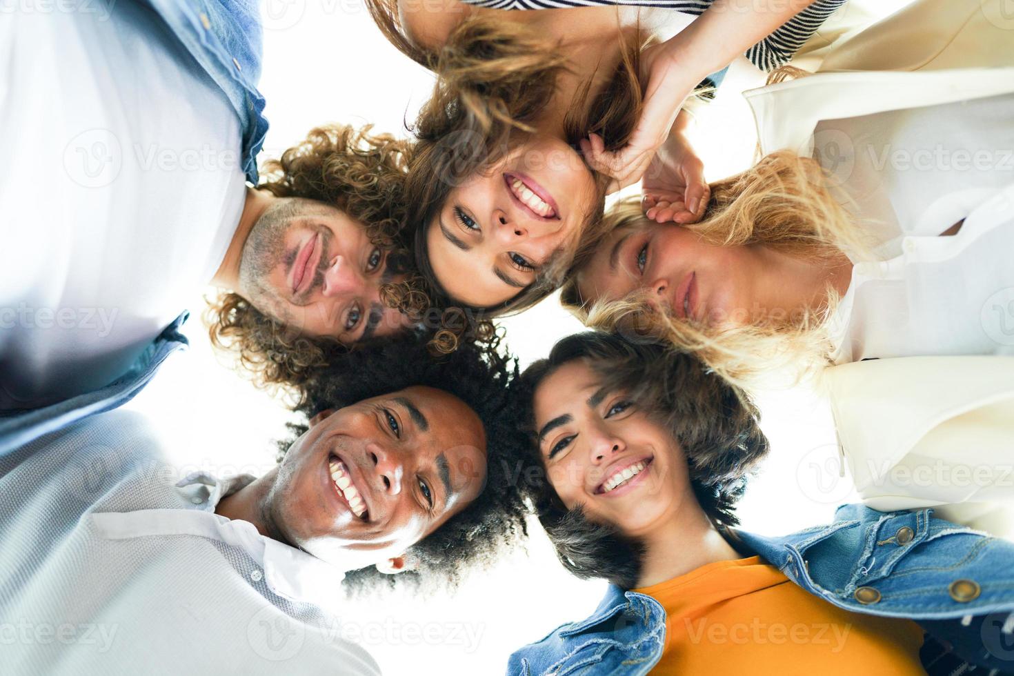 grupo multiétnico de amigos con sus cabezas juntas en un círculo. foto