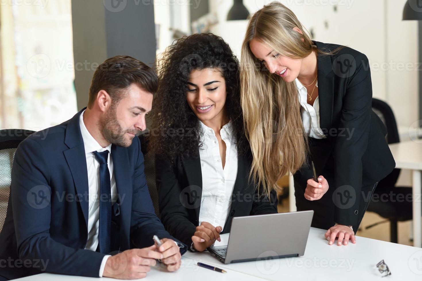 grupo multiétnico de tres empresarios reunidos en una oficina moderna. foto